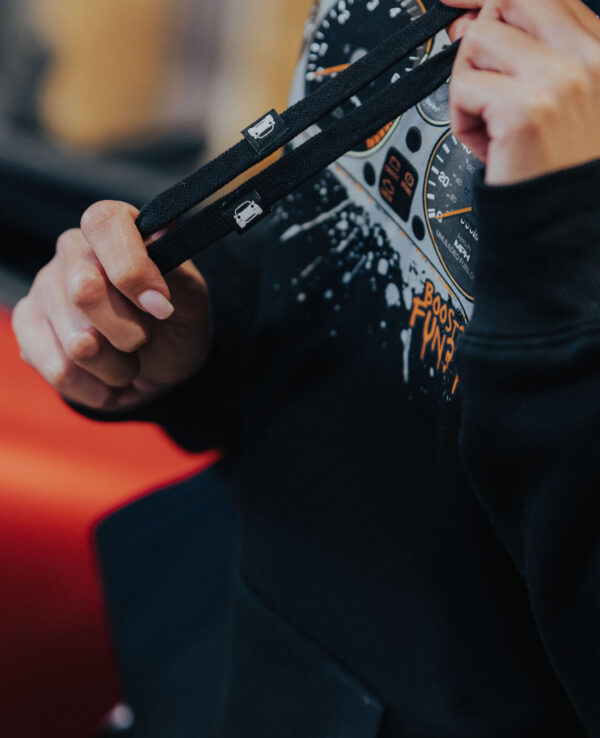 Close-up of a person holding a car keychain with a speedometer design, emphasizing automotive accessories and car enthusiast gear.