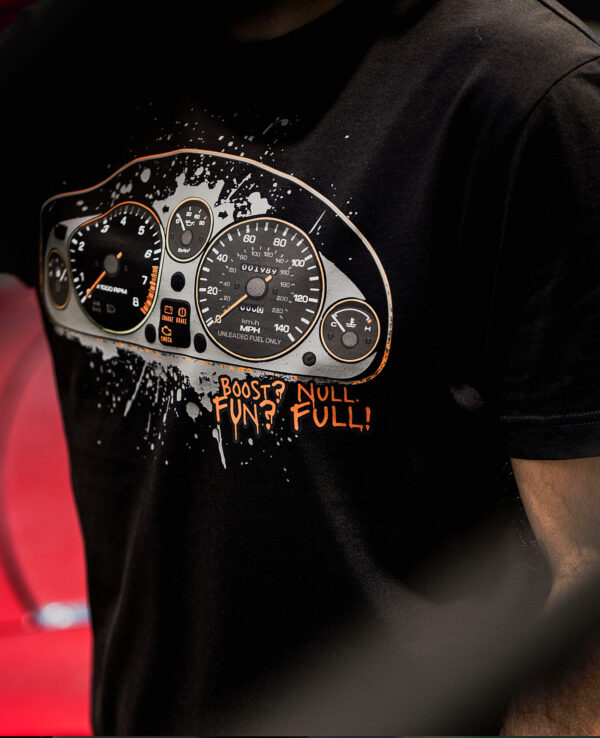 A close-up of a person wearing a black T-shirt featuring a speedometer graphic with the text "Boost? Fun? Null. Full!" perfect for car lovers and Miata enthusiasts.