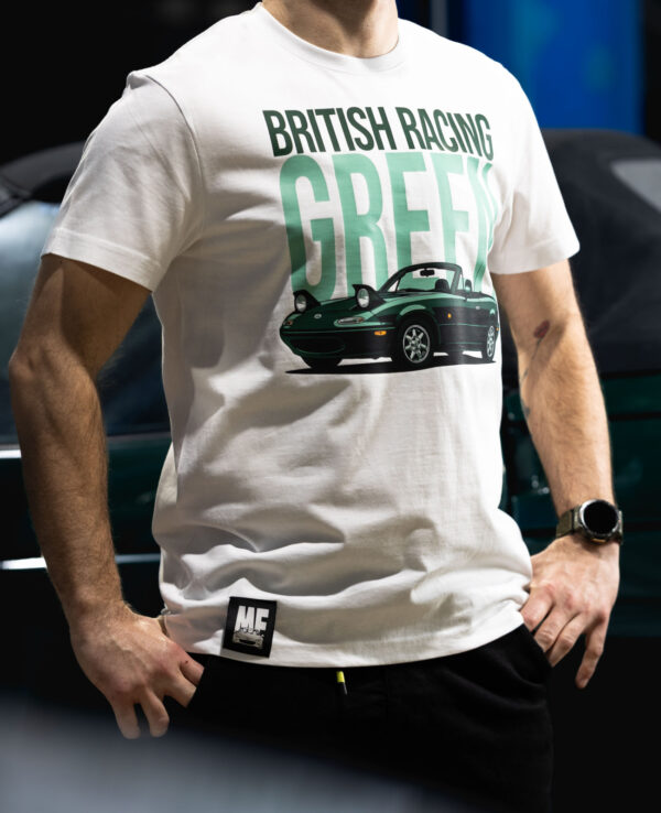 Man wearing a British Racing Green Miata-themed T-shirt at a car event, showcasing Mazda's iconic sports car design and vibrant color.