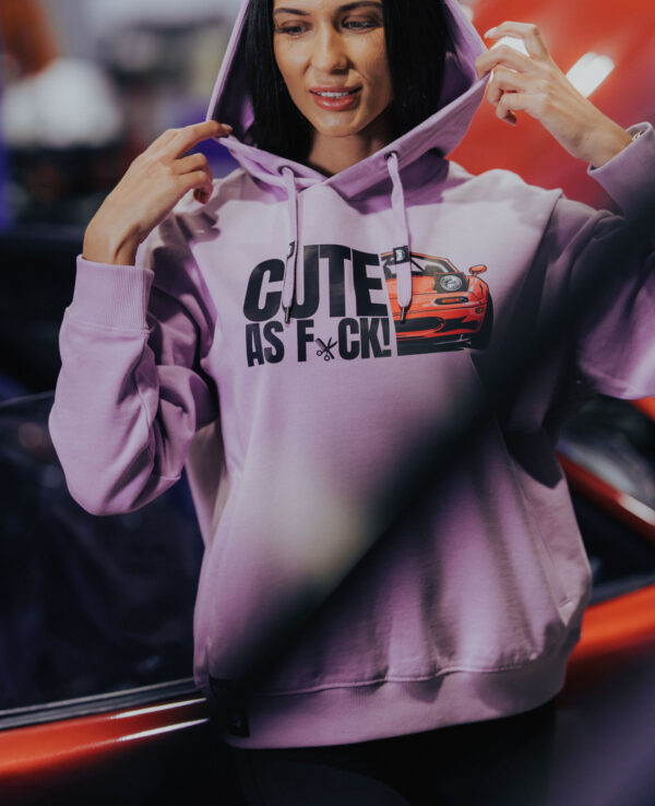 Woman wearing a lavender hoodie with "CUTE AS F*CK" and a Miata car graphic, showcasing automotive passion and stylish casual wear.