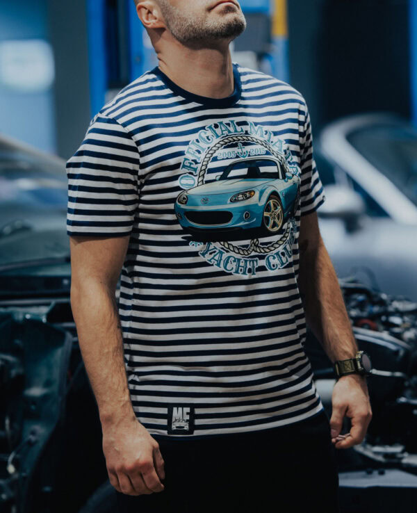 Man wearing a striped T-shirt featuring a Mazda Miata graphic, casual style, in an automotive workshop setting.