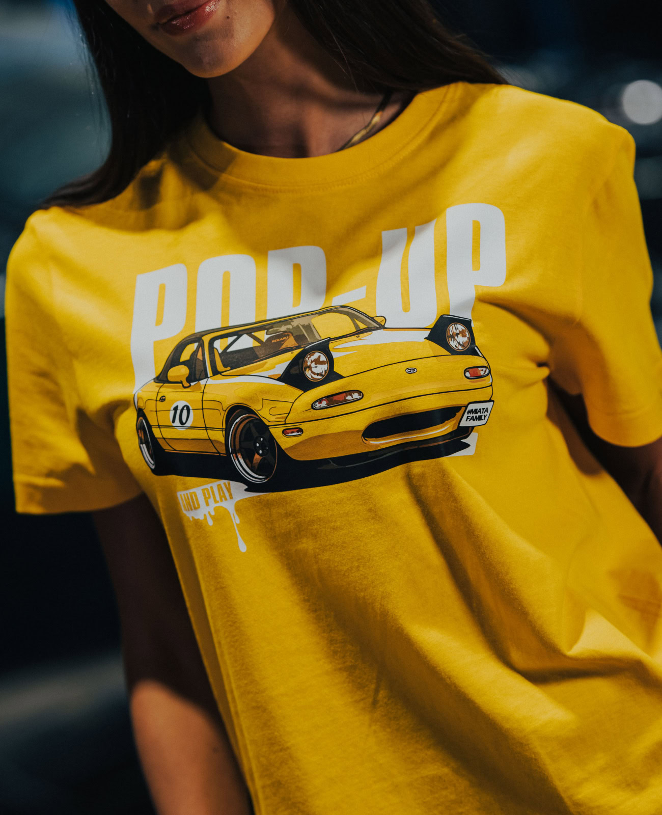 Bright yellow T-shirt featuring a graphic of a sports car with "POP UP" text, perfect for Miata enthusiasts and car lovers.
