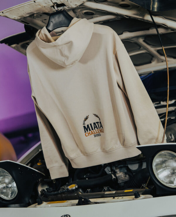 Hoodie with Miata Challenge 2023 logo hanging over car engine.